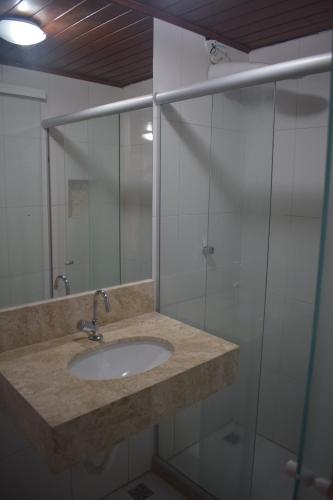 a bathroom with a sink and a glass shower at Pousada Vida Boa in Cabo Frio