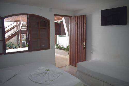 a bedroom with a bed and a window and a television at Pousada Vida Boa in Cabo Frio
