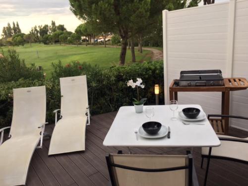 einen weißen Tisch und Stühle auf einer Holzterrasse in der Unterkunft Le Birdy, terrasse, wifi, vélos, Clim in La Grande-Motte
