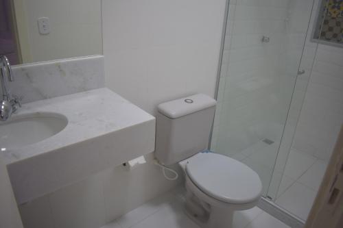 a white bathroom with a toilet and a shower at Pousada Vida Boa in Cabo Frio