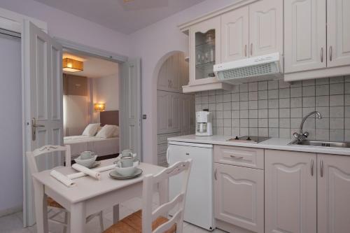a kitchen with white cabinets and a table and chairs at Ammos Naxos Exclusive Apartments & Studios in Naxos Chora