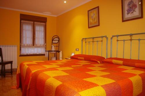 カンガス・デ・オニスにあるLa Vega del Sellaの黄色のベッドルーム(チェック入りの毛布付きのベッド付)