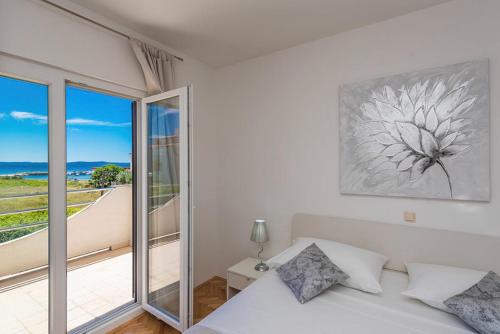 a white bedroom with a bed and a balcony at Villa Marivel in Privlaka