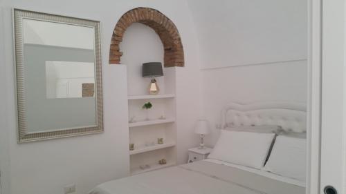 a bedroom with a white bed and a mirror at Suite Pitagora in Bernalda