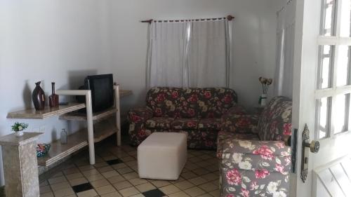 a living room with a couch and a chair and a tv at Casa em Escarpas do Lago in Capitólio