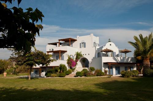 a large white house with a yard at Ammos Naxos Exclusive Apartments & Studios in Naxos Chora