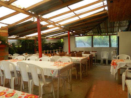 un comedor con mesas, sillas blancas y ventanas en Finca Hotel Nutabes, en San Pedro