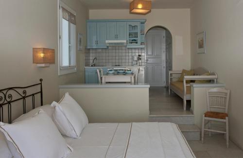 a kitchen with blue cabinets and a bed in a room at Ammos Naxos Exclusive Apartments & Studios in Naxos Chora