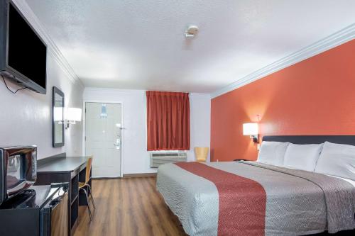 a hotel room with a bed and a desk and a television at Motel 6-Marshall, TX in Marshall