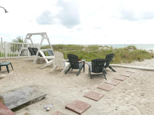 um grupo de cadeiras e uma mesa na praia em Sand Glo Villas em Clearwater Beach