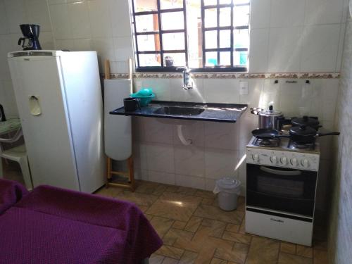 a kitchen with a stove and a sink and a refrigerator at Itaipuaçu Residencia Cajueiros I in Itaipuaçu