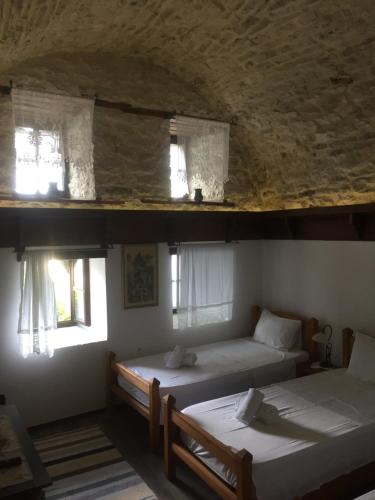 two beds in a room with two windows at Konaku Guest house in Gjirokastër