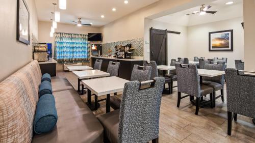 un restaurante con mesas y sillas y un bar en Best Western Mayport Inn and Suites, en Atlantic Beach