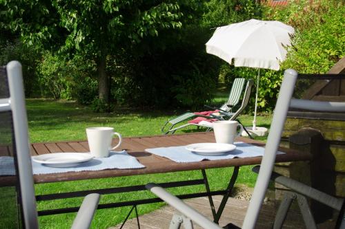 a table with two cups and plates and an umbrella at Ferienhaus am Zylinderberg in Zislow