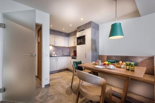 a kitchen and dining room with a wooden table and chairs at Aktiv- & Gesundheitsresort das GXUND - Thermeneintritt inklusive in Bad Hofgastein