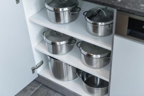 a row of pots and pans on shelves in a kitchen at Aktiv- & Gesundheitsresort das GXUND - Thermeneintritt inklusive in Bad Hofgastein
