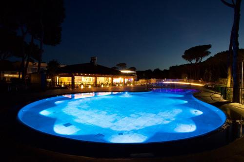 a large blue pool at night with a building in the background at Camping Village Cavallino in Cavallino-Treporti