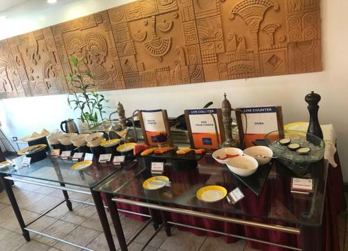 a table with bowls and plates on top at Classic Sarovar Portico Trivandrum in Trivandrum