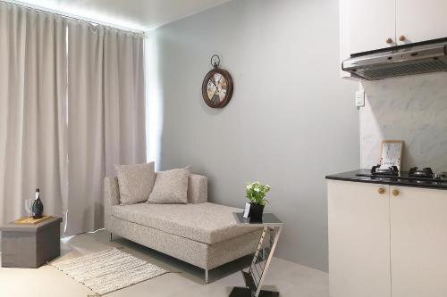 a living room with a chair and a clock on the wall at GM Rentals SafeStay Apartment at Mactan Airport in Mactan