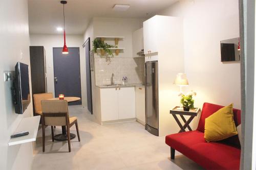 a living room with a red couch and a kitchen at GM Rentals SafeStay Apartment at Mactan Airport in Mactan