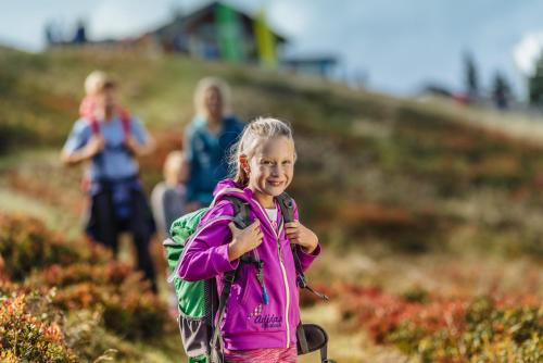 a little girl with a backpack walking down a trail at Aparthotel DAS Hochkönig in Ramsau am Dachstein