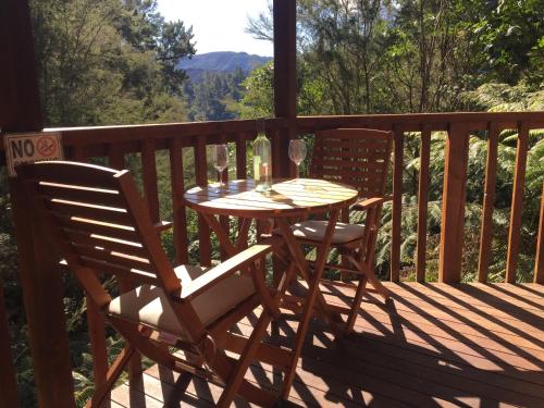 a wooden table and two chairs on a deck at Kanuka Ridge Lodge in Marahau