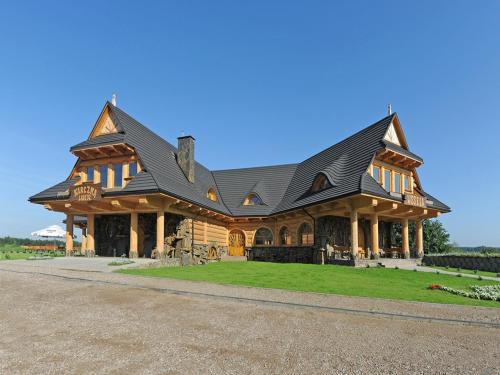 a large log home with a black roof at Łabędź Hotel Karczma in Iława
