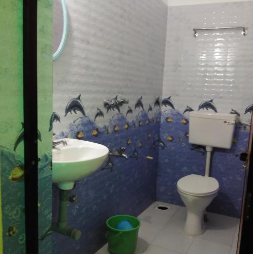 a bathroom with a sink and dolphins on the wall at Luiza Guest House in Baga