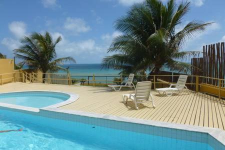una piscina con 2 sillas y una palmera en Flat Beira Mar Praia Ponta Negra, en Natal
