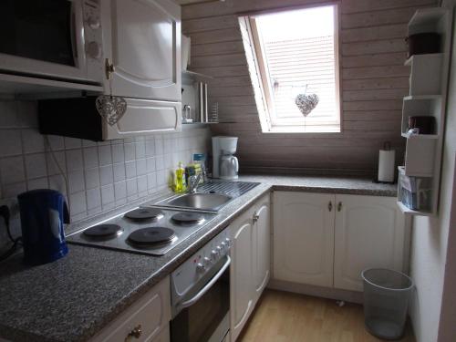 eine Küche mit einem Herd, einem Waschbecken und einem Fenster in der Unterkunft Ferienwohnung Regina in Albstadt