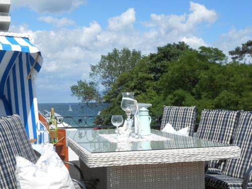 a table with wine glasses on a balcony with the ocean at Haus Midsommer in Timmendorfer Strand