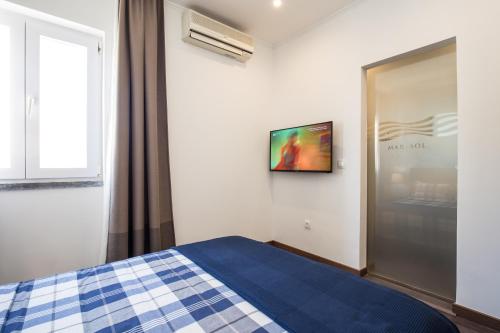 a bedroom with a bed and a tv on a wall at Residencial Mar e Sol in Costa da Caparica