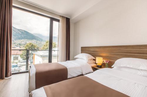 a hotel room with two beds and a large window at Mount Inn Kazbegi in Kazbegi