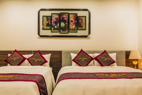 a hotel room with two beds and a picture on the wall at AVA Hotel & Apartment in Danang
