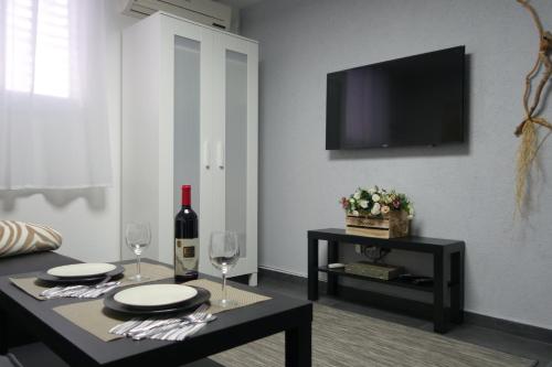 a living room with a table with wine glasses and a tv at Cozy modern apartment near the sea in city center in Netanya