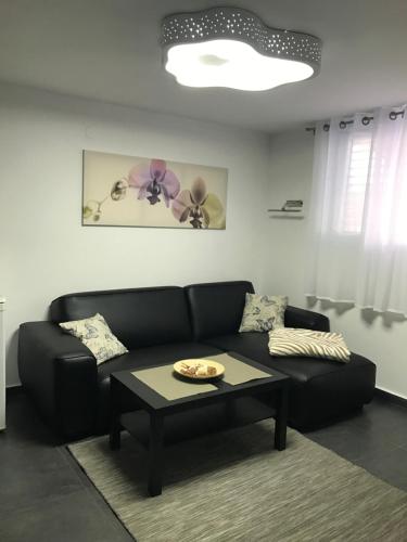a living room with a black couch and a table at Cozy modern apartment near the sea in city center in Netanya
