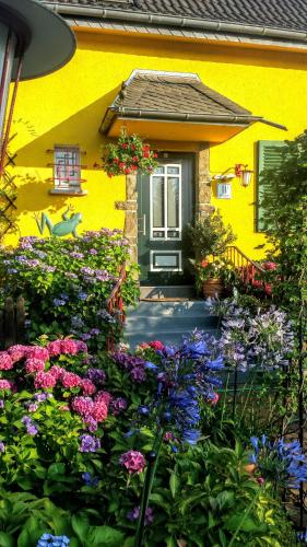 a yellow house with flowers in front of it at Mach mal Pause bei Geni & Bernd in Kleineichen