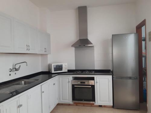 a kitchen with white cabinets and a stainless steel refrigerator at Vivienda Vacacional La Aldea de San Nicolas in La Aldea de San Nicolas