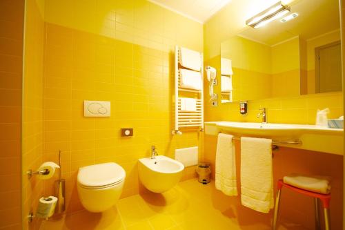a yellow bathroom with a toilet and a sink at Hotel Mercure Venezia-Marghera in Marghera