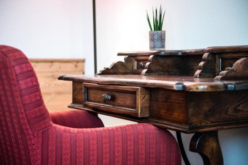 a desk with a red chair and a wooden table with at Sporthotel Exclusive in San Vigilio Di Marebbe
