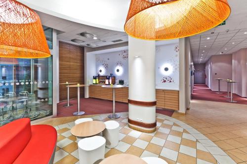 a lobby of a store with red chairs and tables at Ibis Praha Mala Strana in Prague