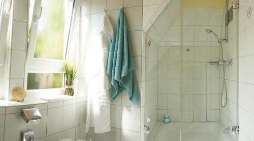 a white bathroom with a shower and a sink at Hotel am Südwäldchen in Westerland (Sylt)