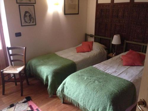 um quarto com 2 camas com lençóis verdes e vermelhos em Il Ciliegio em Imer