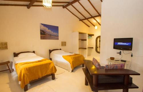 a hotel room with two beds and a tv at Rio Da Barra Villa Hotel in Trancoso