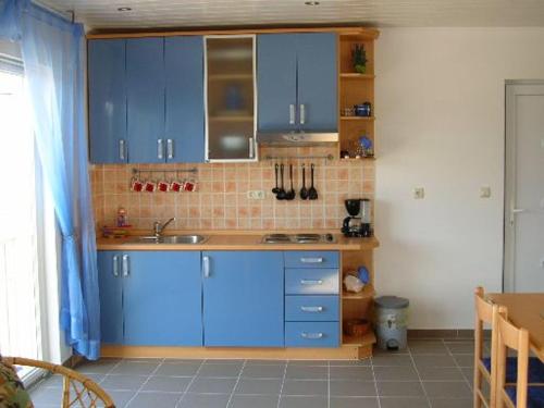 a kitchen with blue cabinets and a tile wall at Waldeck Apartment 1 in Kampor