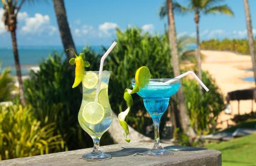 two cocktails sitting on a table next to the ocean at Rio Da Barra Villa Hotel in Trancoso