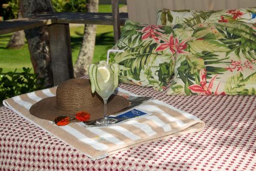 a straw hat and a glass of wine on a table at Rio Da Barra Villa Hotel in Trancoso