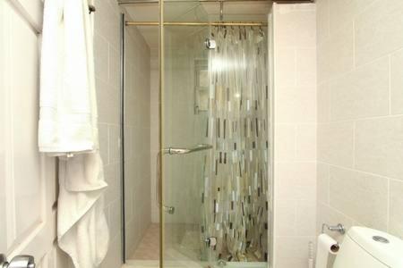 y baño con ducha y puerta de cristal. en Sungold House Barbados en Saint Peter