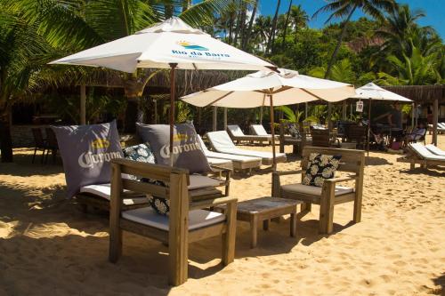 a group of chairs and umbrellas on a beach at Rio Da Barra Villa Hotel in Trancoso