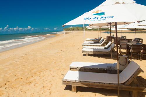 a beach with chairs and umbrellas on the sand at Rio Da Barra Villa Hotel in Trancoso